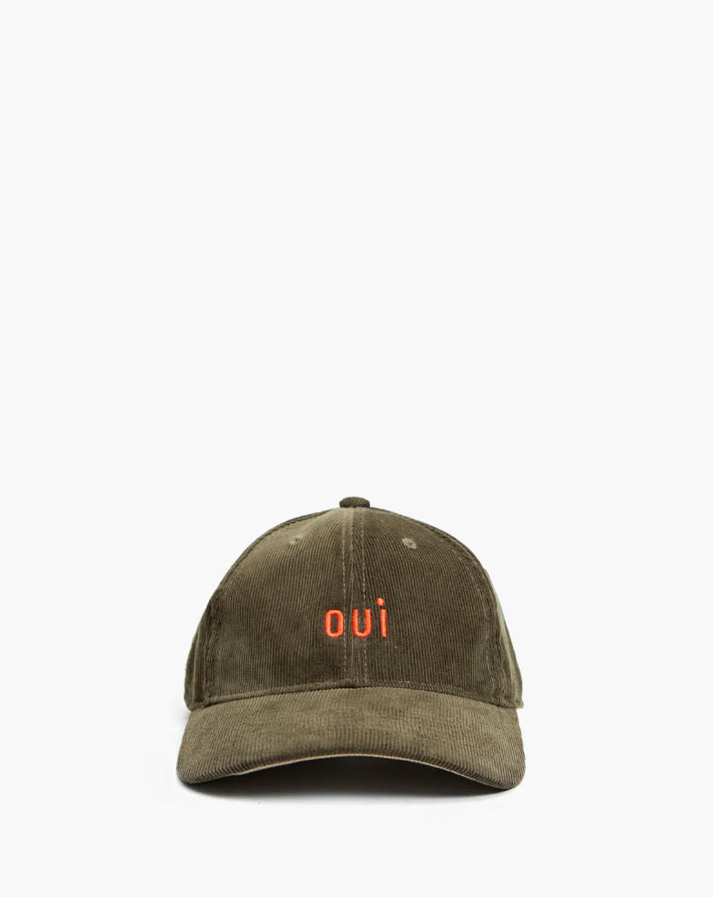 A worn Clare Vivier olive green baseball cap in Arizona style with the word "OUI" embroidered in orange on the front, isolated against a white background.
