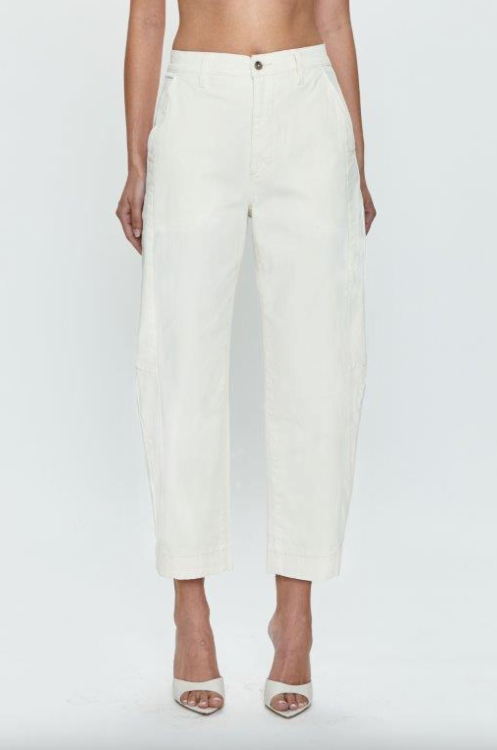 A woman wearing Pistola&#39;s Eli High Rise Arched Trouser, white, cropped, wide-leg pants and white sandals, shown from the waist down against a plain background.