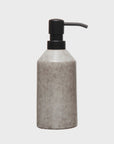 A stoneware soap dispenser from Bloomingville with a speckled gray finish and a black pump, isolated on a white background, reminiscent of Scottsdale Arizona aesthetics.