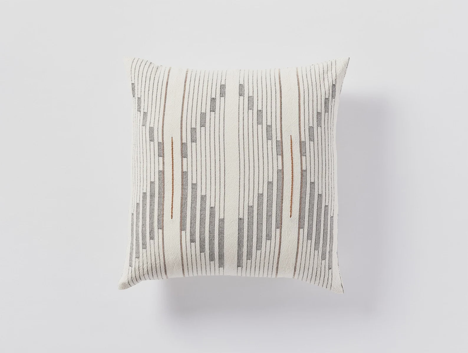A Coyuchi Inc decorative pillow with a textured, striped pattern in neutral tones of white, gray, and beige, pictured against a clean, white background typical of a Scottsdale Arizona bungalow.