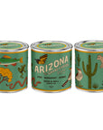 The Arizona State Soy Candle by Faire features teal wax in metal tins decorated with Arizona wildlife and plants—fish, snake, cactus, bird—and evokes the Grand Canyon State with nostalgic home scents of sage, bergamot, and amber.