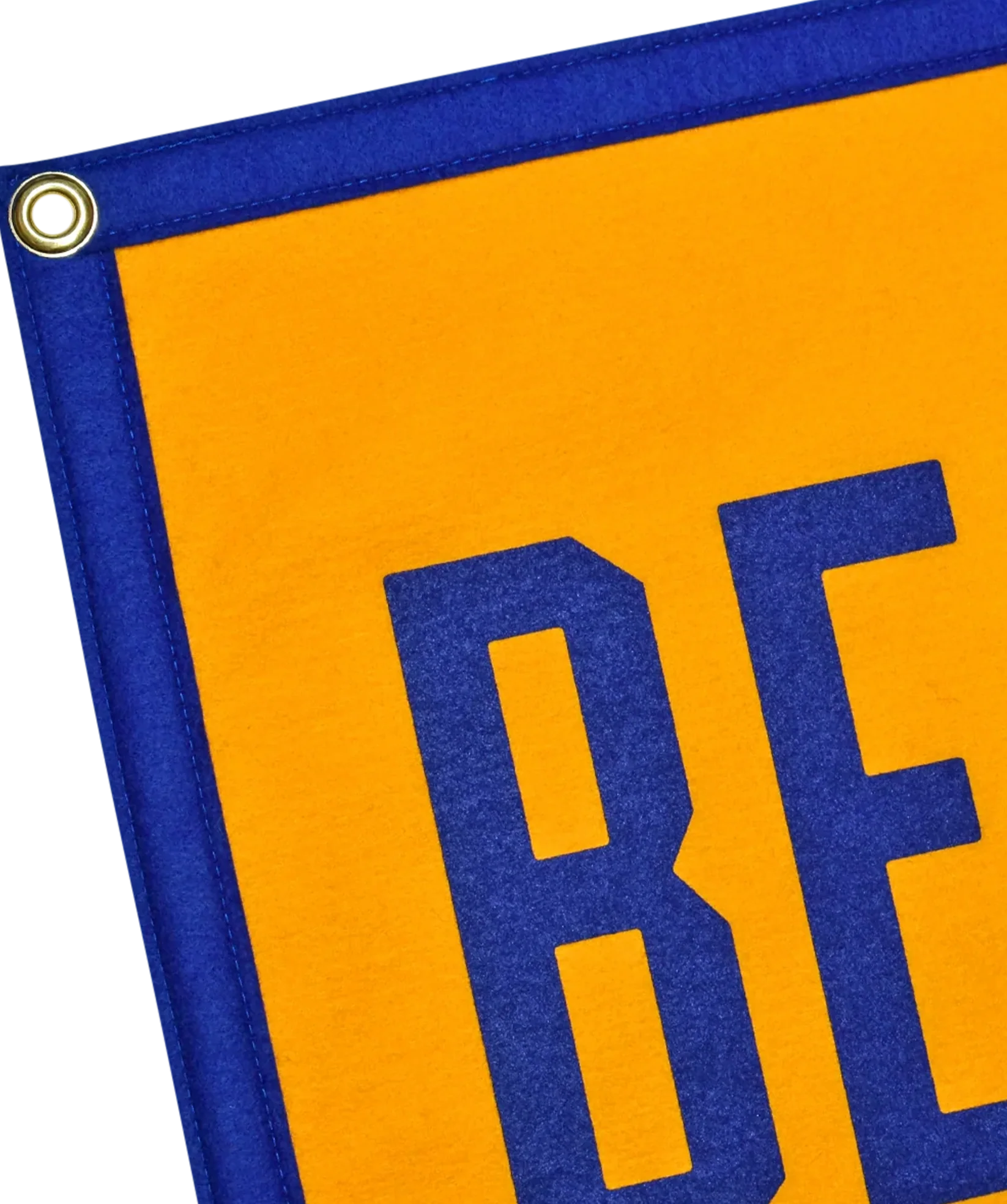 Close-up of the Oxford Pennant "Believe Camp Flag 16x24," made from yellow and blue wool felt with a metal grommet. The screen-printed design features large blue "BE" letters.
