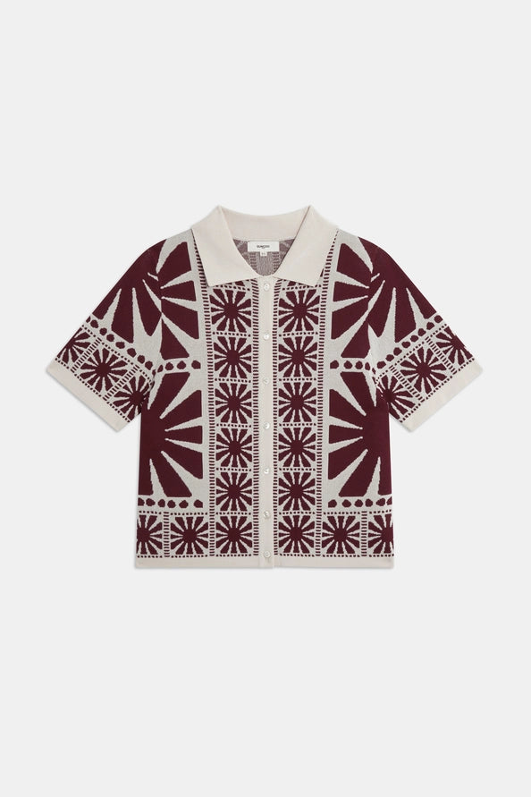 The Gabera Shirt by SUNCOO is a short-sleeved jacquard knit cardigan in beige with maroon starburst and border patterns, featuring a collared neckline and front button closure.