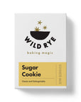 A box of Wild Rye Sugar Cookie Mix featuring a minimalist design with gold stars, a black bowl, and a yellow label reading "Sugar Cookie: Classic and Unforgettable," made with organic ingredients for delicious buttery cookies.