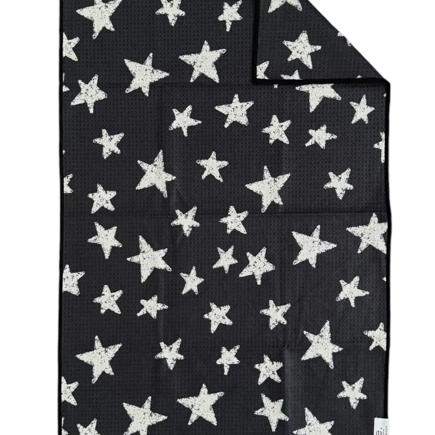 The Faire Double Sided Hand Towel is a black, rectangular waffle weave microfiber towel with white, irregular star patterns on both sides. One corner is folded to show the reverse's matching design.