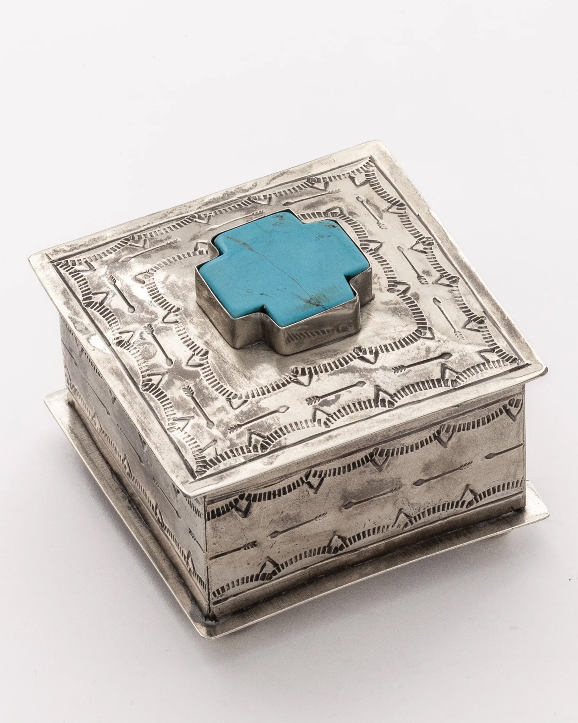 The Small Stamped Box w/ Turquoise Cross by J Alexander Rustic Silver features a raised turquoise cross and bold geometric designs—ideal for Southwestern décor. Photographed on a plain white background.