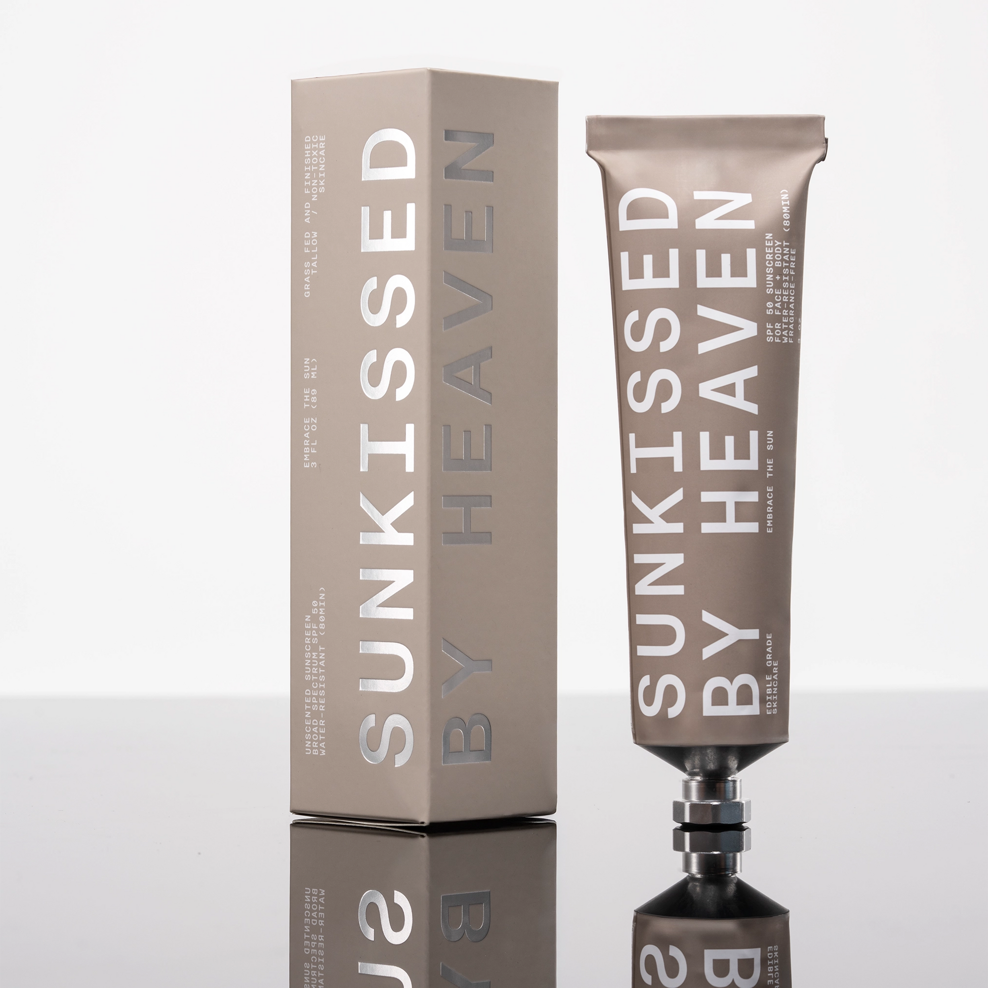 A metallic tube and matching box labeled "Tallow Sunscreen SPF 50" by Faire stand upright on a glossy surface, highlighting this sensitive skin sunscreen against a crisp white background.