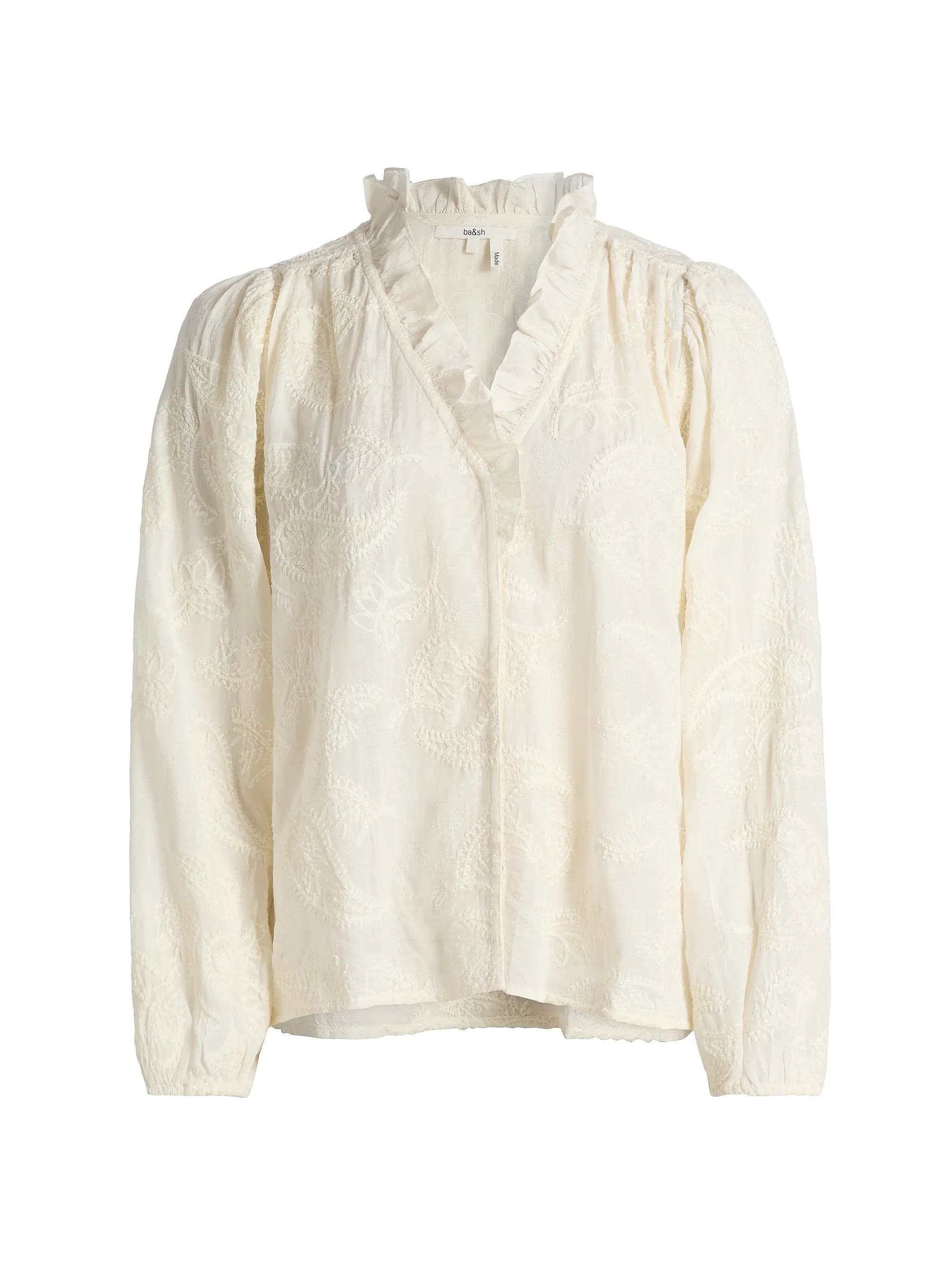 The BA&SH Shirt Petty is a cream bohemian blouse featuring subtle paisley embroidery, a ruffled V-neckline, and gently puffed long sleeves.