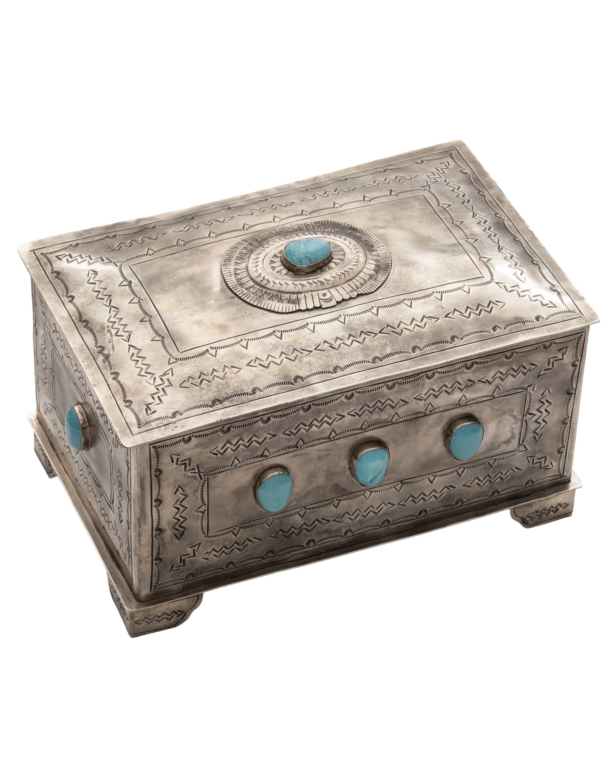 The J Alexander Rustic Silver 82-1-T 9 Stone Turq Box is a rectangular silver box with engraved patterns and nine turquoise stones on the lid and sides, ideal as Southwestern decor while standing elegantly on four small feet.