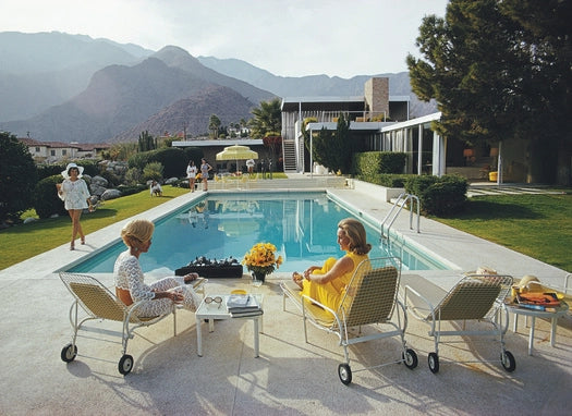 Gather around the poolside chic of Pieceworks Puzzle 1000 by Faire, where midcentury style, mountain views, and lush lawns set the scene as women relax and chat, with flowers and drinks adding charm to this stylish puzzle.