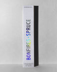 A white rectangular box of Faire Incense Sticks stands upright against a light gray background. "BONFIRES + SPRUCE" is in holographic text, with notes of Sandalwood Resin and "BY FAIRE" in smaller text at the top.