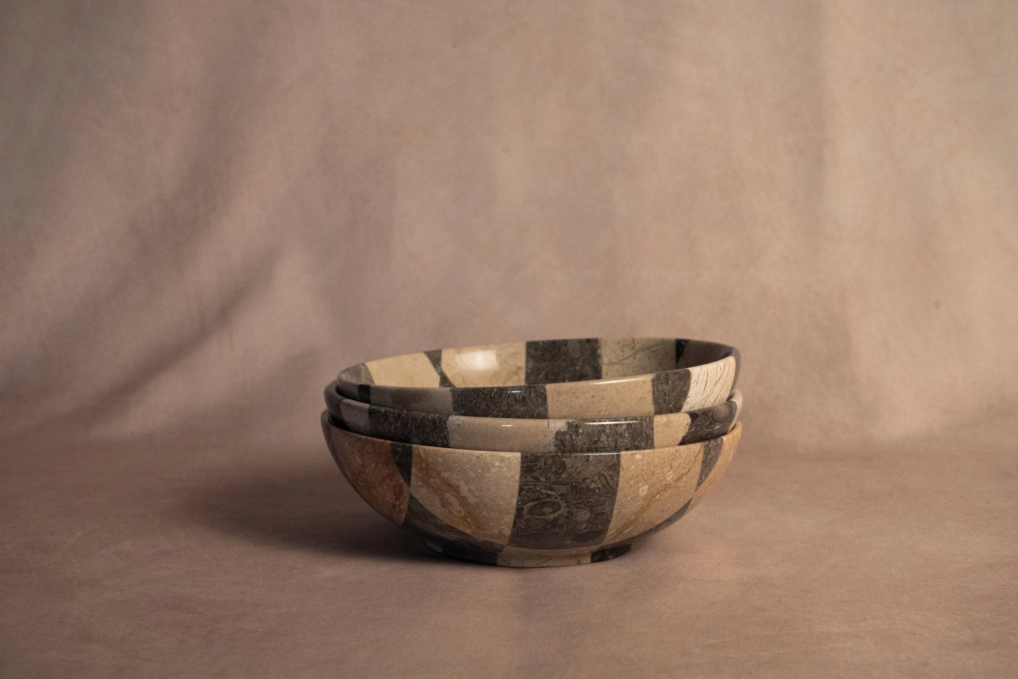 Round travertine checkered bowl by Faire, handcrafted centerpiece for modern living or dining rooms.