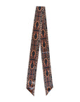 The Faire Western Harvest Twilly scarf features a narrow silk design with pointed ends and a hand-drawn pattern of brown horseshoes and abstract shapes on a dark background.