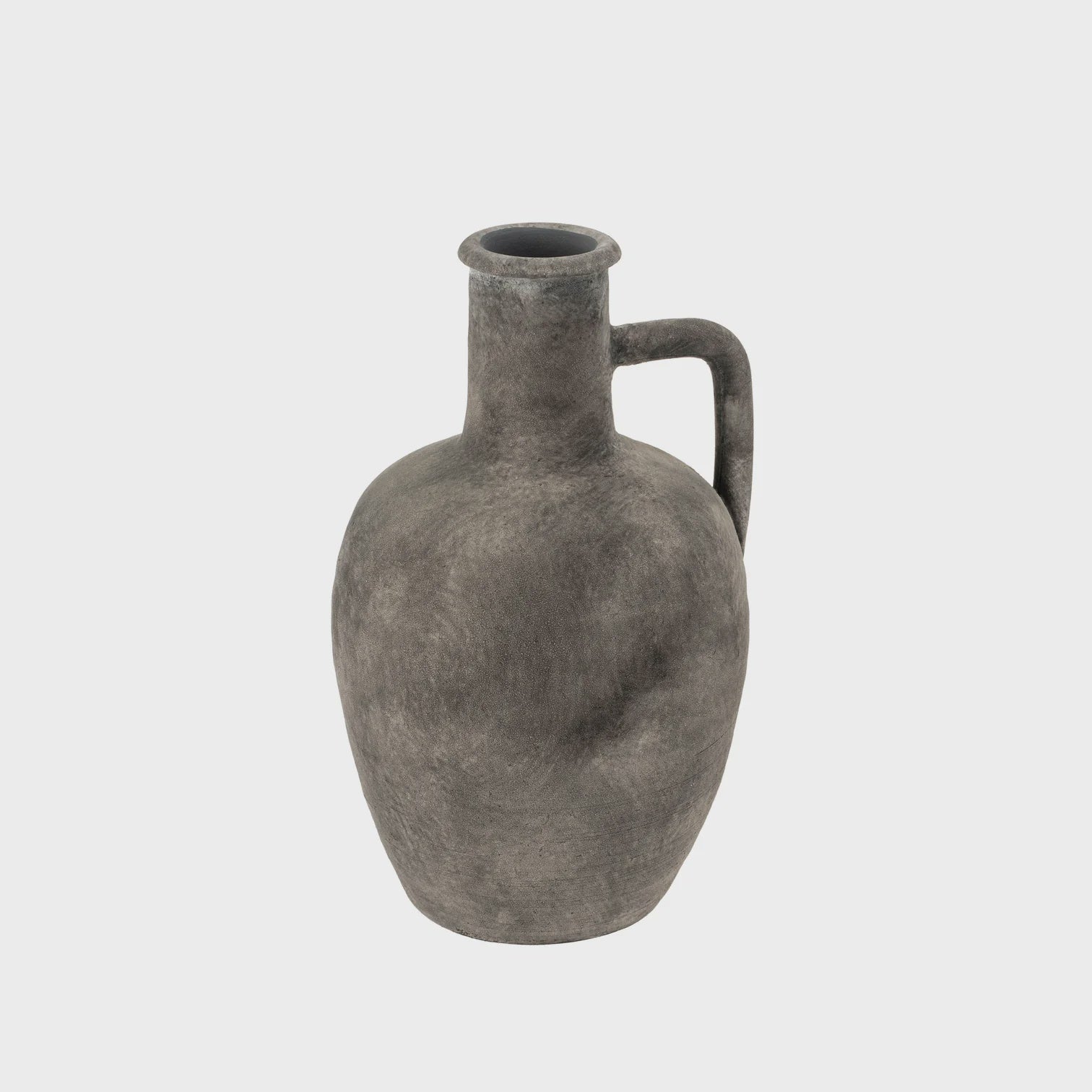 The Pau Terracotta Vase by Indaba features a weathered, ancient-looking design with a narrow neck, single handle, and rounded body, sitting gracefully against a plain white background and embodying timeless antique forms.