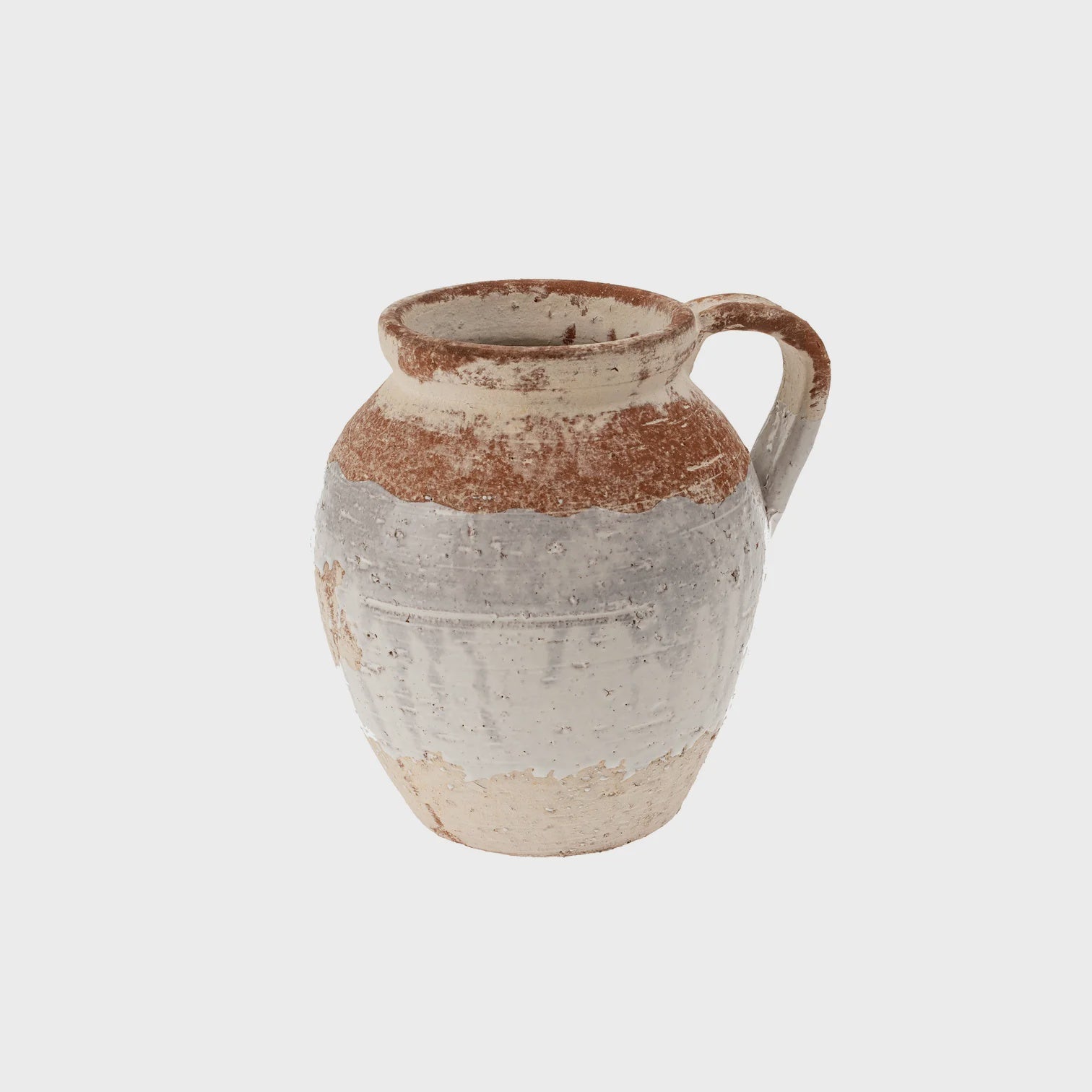 The Vichy Terracotta Vase by Indaba is a rustic, handcrafted piece with a handle that boasts a textured surface and visible wear. Its unique design transitions from reddish-brown at the top to a faded gray and cream at the bottom, evoking an aged, weathered appearance similar to a vintage clay jug.