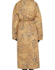 A person wearing the Classic Sleeping Bag Coat from Norma Kamali, featuring a long leopard print design reminiscent of the iconic sleeping bag coat style, stands facing away, highlighting its detailed pattern and oversized silhouette with black gloves and boots.