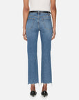 A person is seen from the back wearing FRAME’s The Ruler Crop blue high-waisted slim-straight jeans with frayed hems, two back pockets, styled with black heeled shoes and a white top.