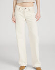 Wearing FRAME’s The Saturday Jean—high-waisted, straight-leg white jeans in 100% cotton rigid denim—with tan pointed-toe shoes and a cropped beige sweater; photo shows the look from shoulders down against a plain background.