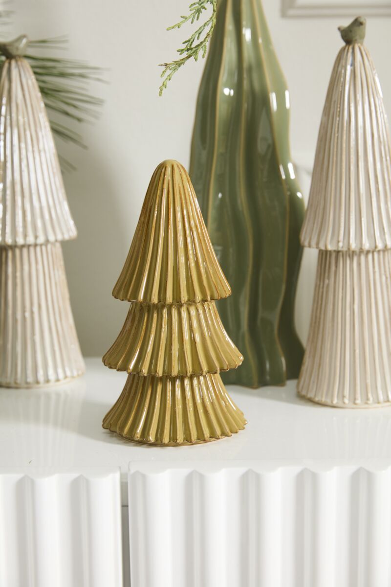 The Village Tree Small by Accent Decor, a gold ceramic tree figurine, is showcased on a white surface among white and green tree sculptures, forming a festive holiday display inspired by the Village Collection.