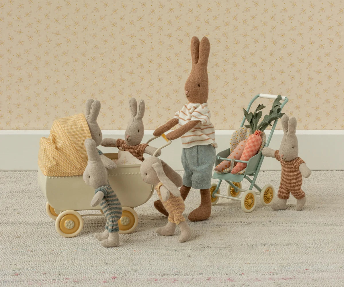 Maileg Micro Pram with carrots and playful bunnies on an indoor rug, styled for a cozy nursery or playroom.