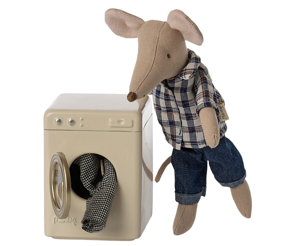 A Maileg mouse in a plaid shirt and jeans stands next to the Maileg Washing Machine, with a small piece of laundry visible through the open door.