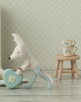 A small fabric mouse in blue pants holds a blue heart-shaped box with a tooth image. Next to it are two stacked teacups on the Maileg Table & Stool by Maileg, with a milk carton and patterned wallpaper in the background.