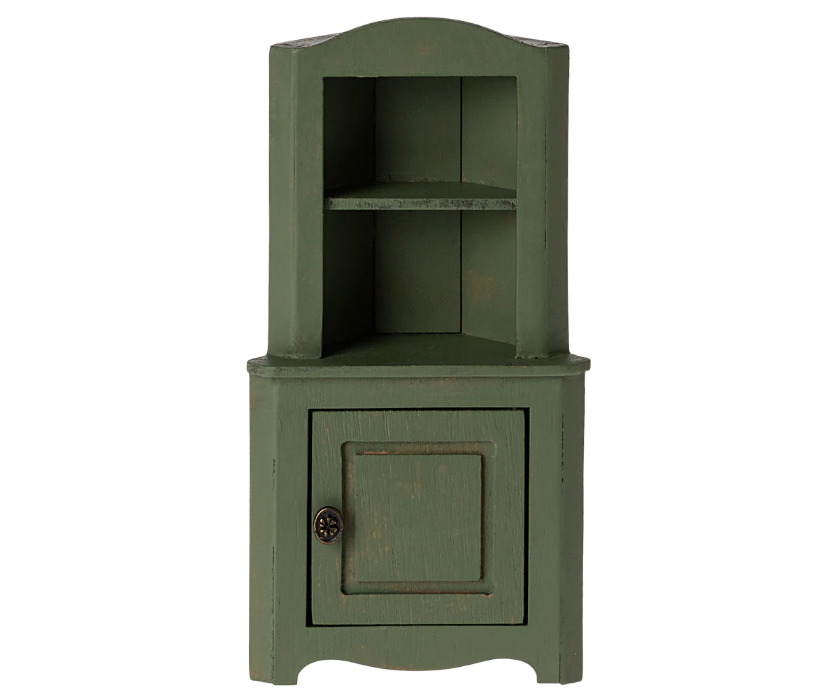 The Maileg Furniture by Maileg is a small green wooden corner cabinet for dollhouses, featuring an upper open shelf with two sections and a lower cupboard door with a round handle, shown against a plain white background.