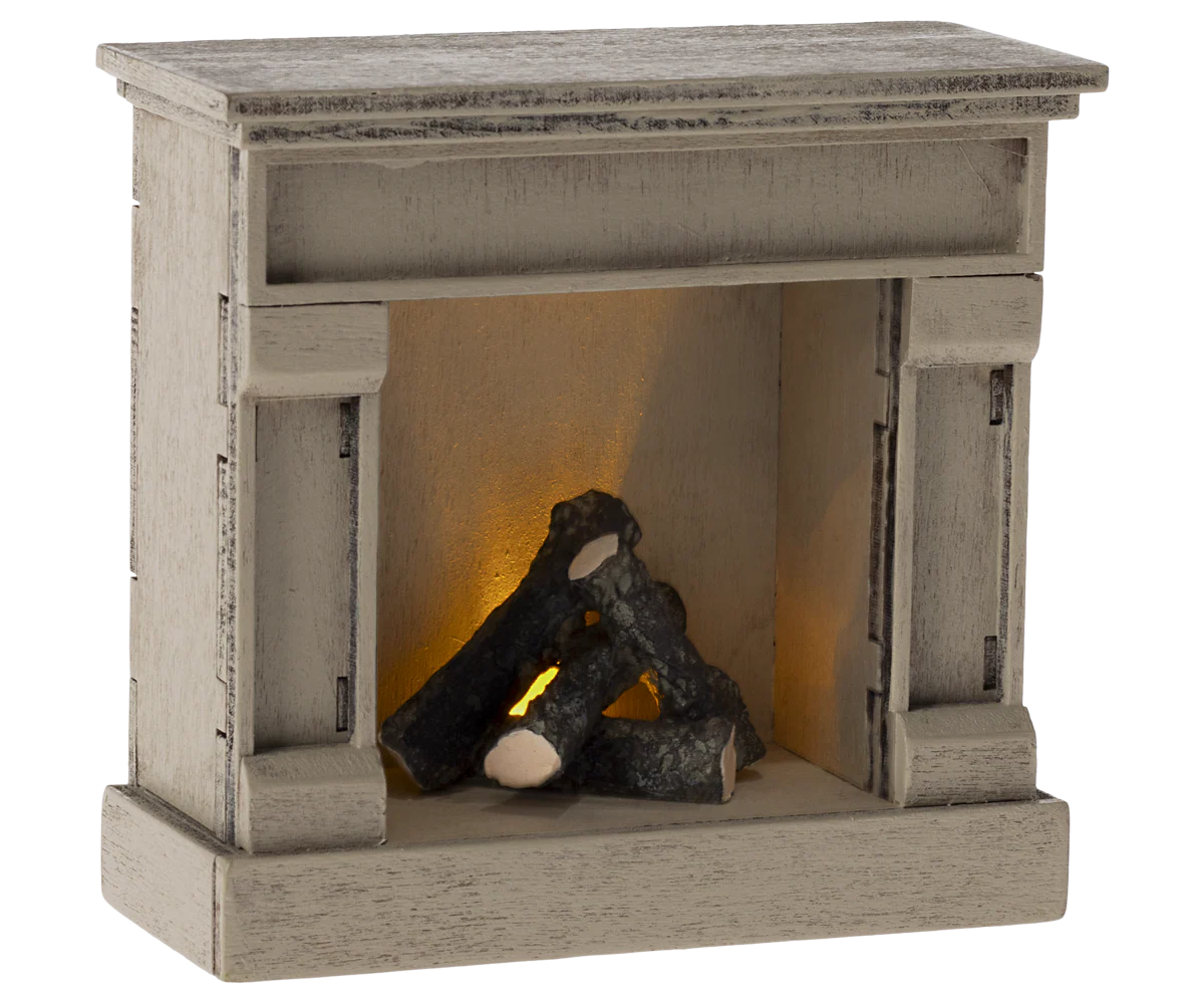 The Maileg Fireplace by Maileg is a small, vintage-finished wooden piece with faux logs and a warm glow, perfect for cozy mouse homes or rustic décor and styled to resemble a classic hearth.
