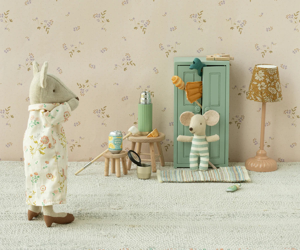Maileg’s Closet creates a cozy scene with a fabric mouse in pajamas facing another in stripes by the green Maileg Closet. Miniature furniture, snacks, golden hangers, and pastel details add a whimsical touch from the beloved Maileg brand.