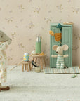 Maileg’s Closet creates a cozy scene with a fabric mouse in pajamas facing another in stripes by the green Maileg Closet. Miniature furniture, snacks, golden hangers, and pastel details add a whimsical touch from the beloved Maileg brand.