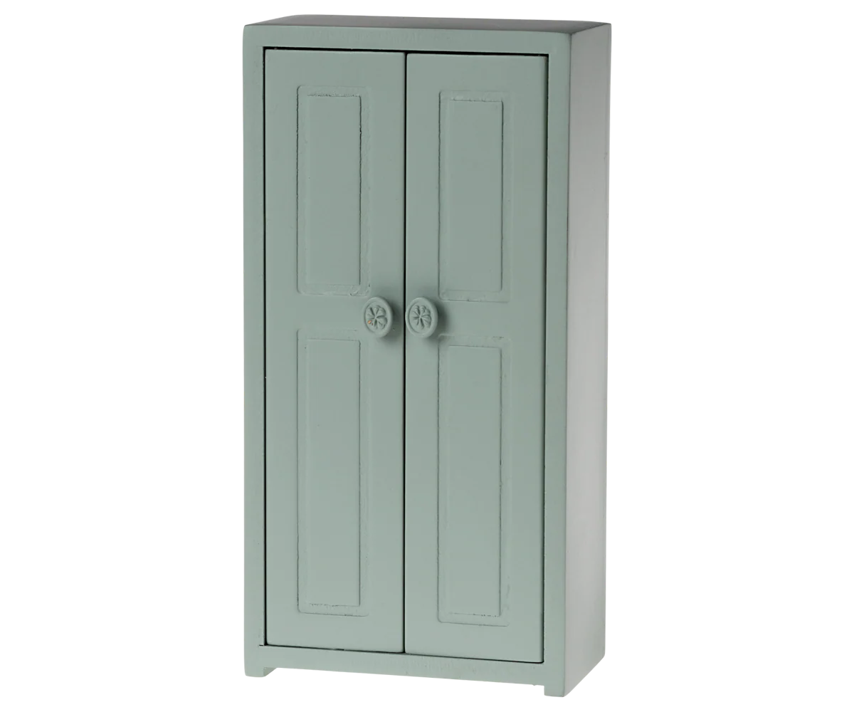 The Maileg Furniture by Maileg is a light green wooden cabinet with two paneled doors and round knobs, standing on four short legs—ideal for dollhouse setups or Maileg Mouse, featuring a simple and classic design.