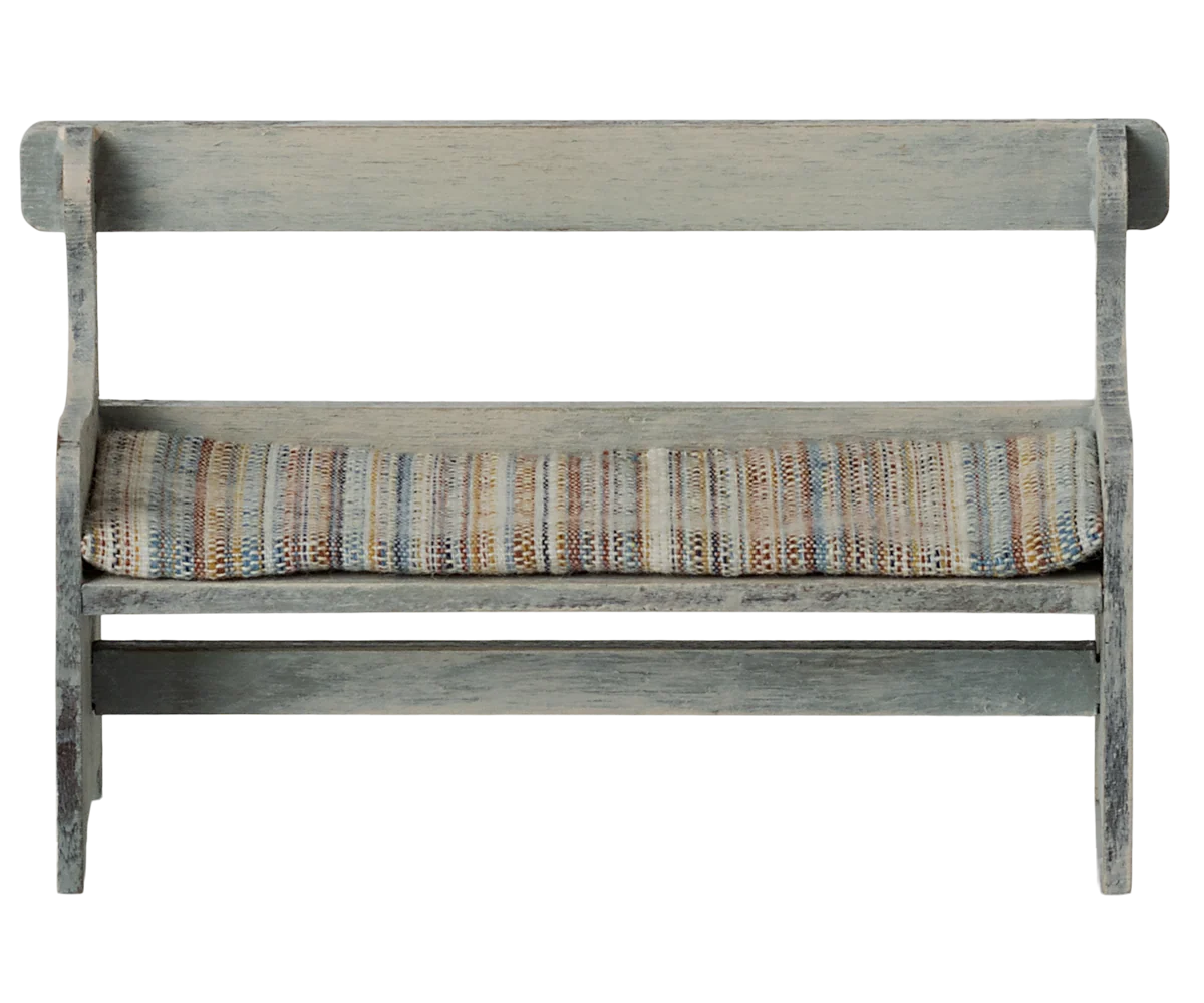 The Maileg Bench by Maileg features a small vintage design with a distressed gray finish and a woven multicolored seat cushion, shown on a white background—perfect for bunny furniture or adding whimsical décor to any space.