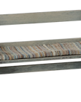 The Maileg Bench by Maileg features a cushioned seat with striped, multicolored fabric, backrest and arms. Its weathered grayish wood finish adds vintage charm to this classic small bench.