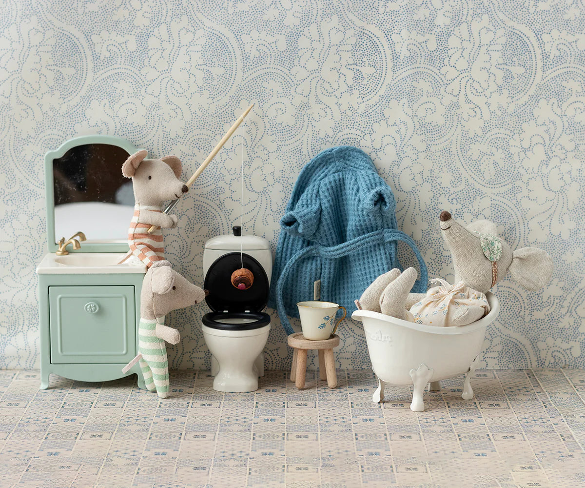 Three Maileg mice in pajamas play in a tiny bathroom with Maileg accessories, including the vintage-inspired Maileg Bathtub. One mouse fishes in the toilet, another relaxes in the tub, and the third stands nearby.