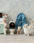 Three Maileg mice in pajamas play in a tiny bathroom with Maileg accessories, including the vintage-inspired Maileg Bathtub. One mouse fishes in the toilet, another relaxes in the tub, and the third stands nearby.