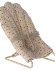 The Maileg My Babysitter by Maileg is a small, fabric-covered doll chair with a metal base, a beige seat with colorful dots, and an attached strap—perfect for keeping dolls secure and comfy.