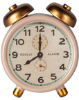 The Maileg Alarm Clock by Maileg is a small vintage-style metal clock with gold bells and legs, displaying 8:00. Its face shows black numbers, "REPEAT" and "ALARM," plus two extra dials above and below the center.