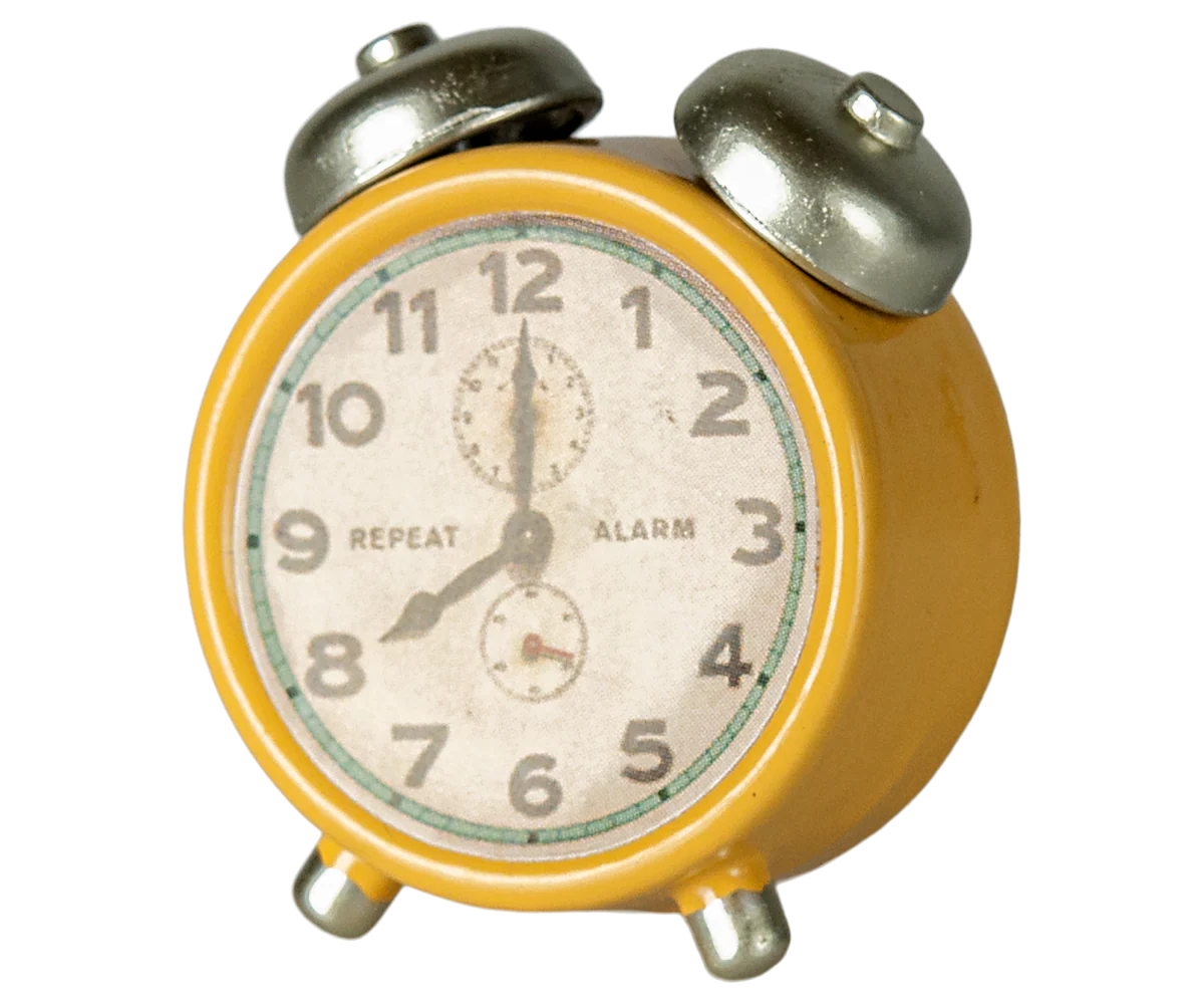 The Maileg Alarm Clock is a yellow vintage-style metal clock with two silver bells, bold black numbers, and "REPEAT" on the left and "ALARM" on the right of the face. This small, classic timepiece displays 7:04.
