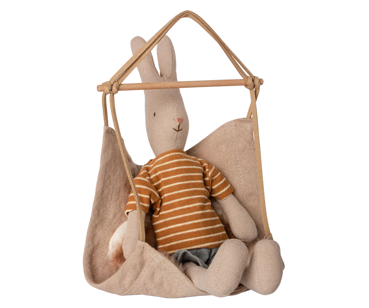 The Maileg Hanging Chair by Maileg features a beige fabric seat hanging from wooden rods, ideal as charming dollhouse furniture or for displaying small stuffed animals.