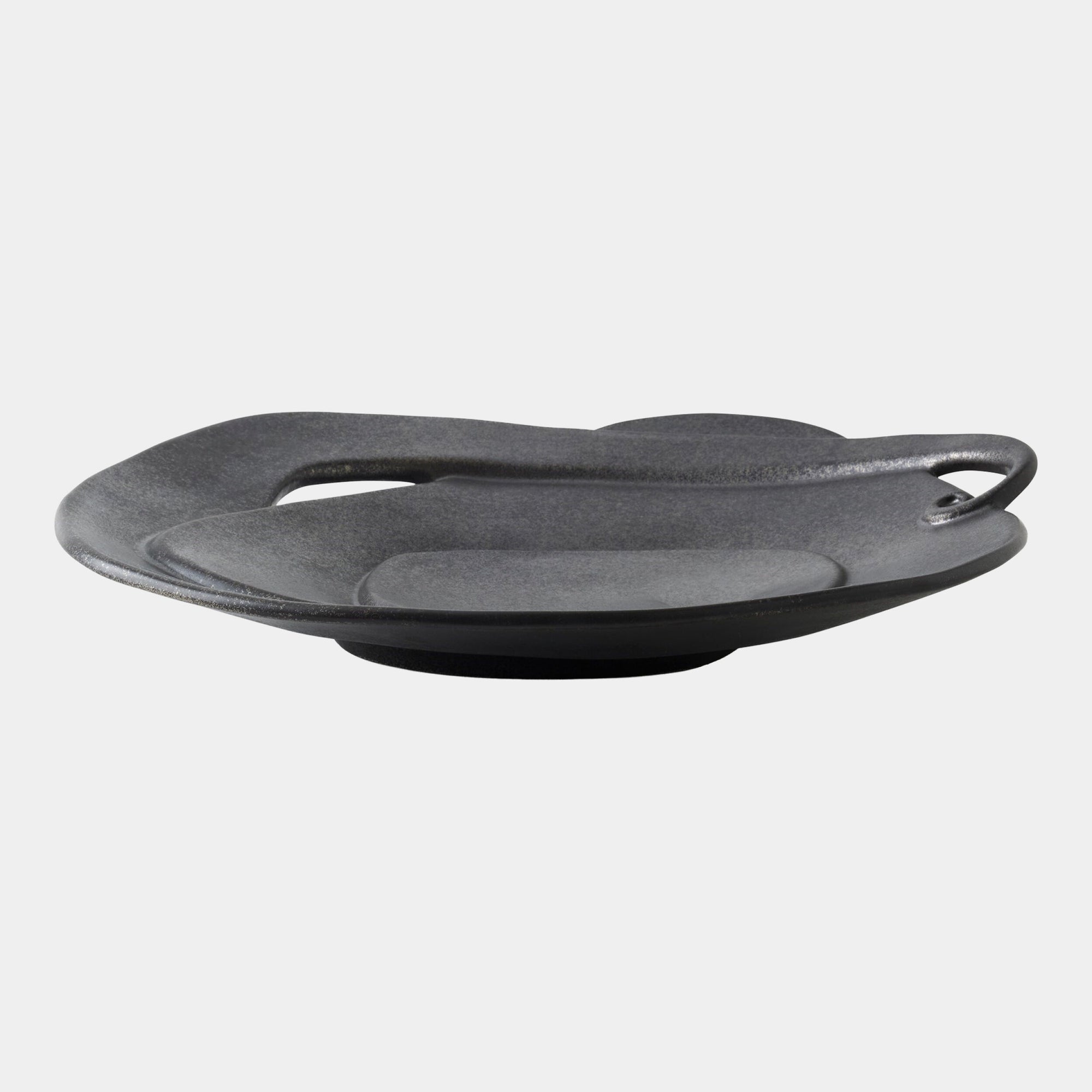 The Global Views Spiral Plate Black features a modern, sculptural ceramic design with black glaze, an irregular organic shape, slightly elevated base, and a small curved handle—strikingly displayed against a plain white background.
