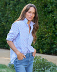 Standing outside amidst lush greenery, a long-haired individual wears the Eileen striped button-up by Frank & Eileen paired with jeans, hands comfortably in pockets.