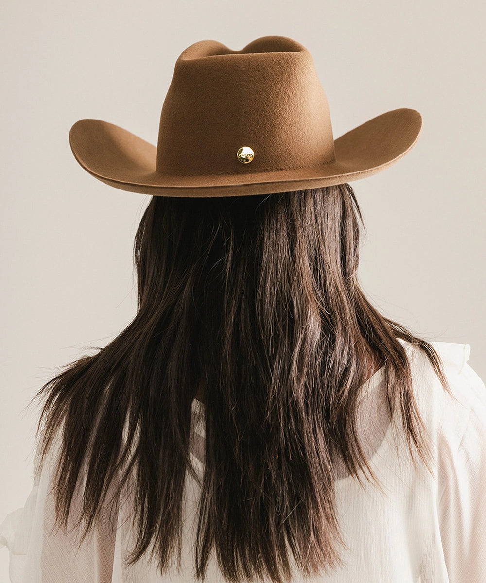 A person with long brown hair and a light shirt is seen from behind wearing the Faire Charlie Western Hat, set against a neutral background.