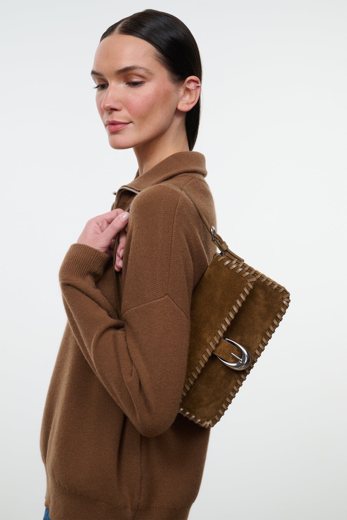 Staud Harlow Bag in brown suede with stitching detail and silver buckle, carried over shoulder with casual style.