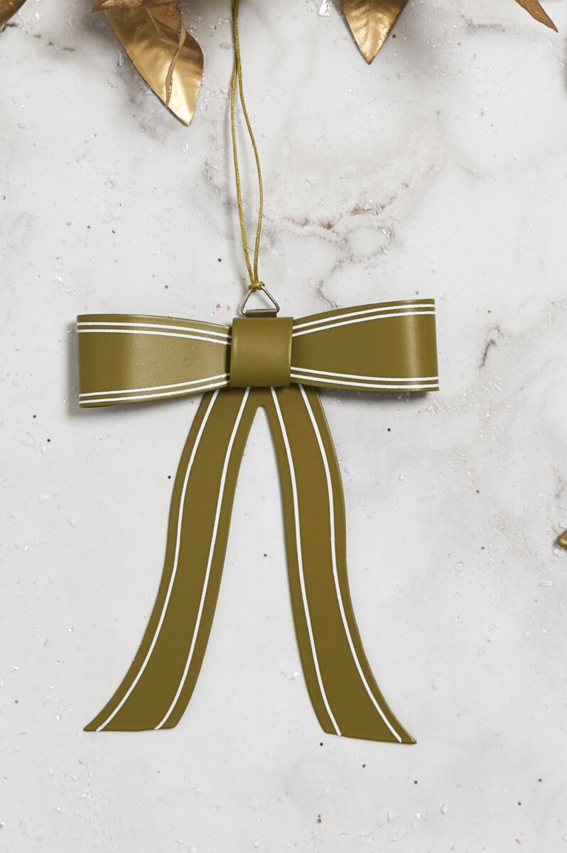 The Accent Decor Saleh Bow Ornament 4.75x5.5", in metallic olive green with white trim and gold leaves, hangs by a gold string against a marble background—an eye-catching metal Christmas tree decoration.