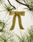 The Selah Bow Ornament 6x7.5" by Accent Decor adds festive charm to your Christmas tree, hanging elegantly from a pine branch with green needles against a plain light background.