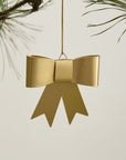 The Accent Decor Perfect Bow Ornament, featuring ribbon tails, hangs from a pine branch against a light background—adding an elegant touch to your holiday décor.