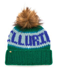 The Faire Knit Ski Hat is a luxury green beanie with blue and light blue patterns, a large brown faux fur pom pom, and a gold flower pin on the cuff.