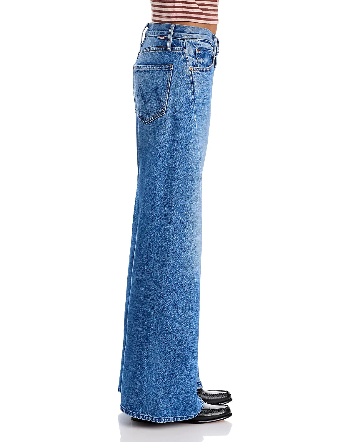A person in light blue high rise five-pocket jeans, a brown and white striped top, and Mother’s The Lemon Twist Sneak shoes (black, pointed), shown in profile view.