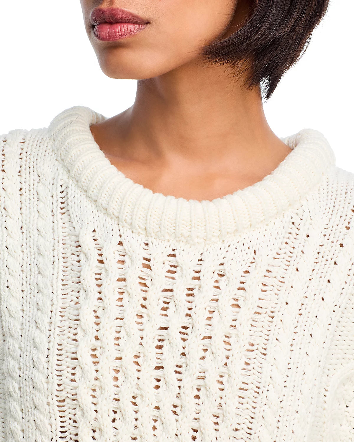 A woman wears the Denimist OVERSIZED ARAN SWEATER, a white cotton knit made from heavyweight fabric with a wide ribbed collar. Only her lower face, neck, and upper torso are visible.