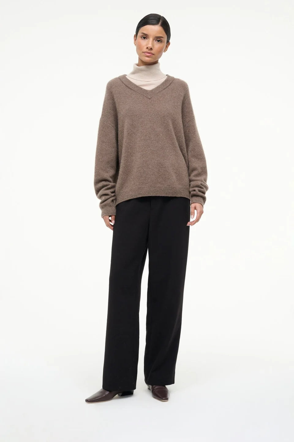 Brown V-neck sweater layered over beige turtleneck, paired with black pants and Staud Wally Sock Flat boots.